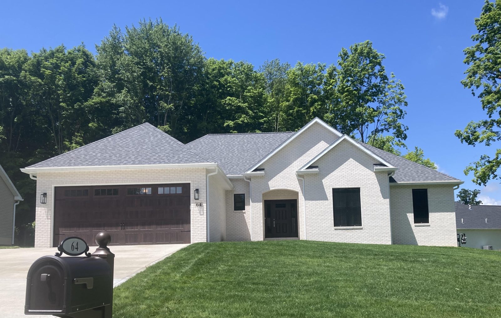 Charcoal board-and-batten ranch with three-car garage and teal front door