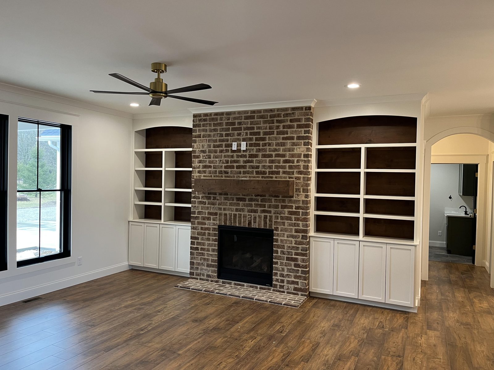 Reclaimed brick fireplace flanked by white built-in bookshelves with walnut interiors