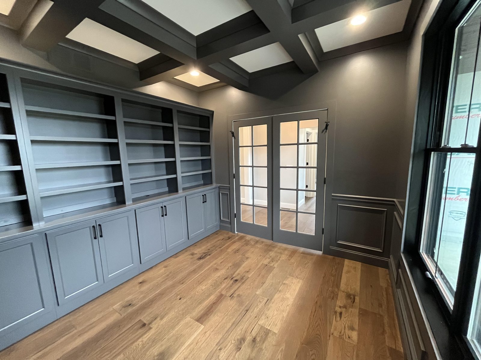 Home office with coffered ceiling and full built-in bookshelves in deep gray